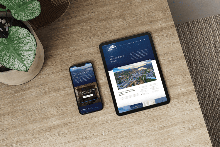 Tablet and smartphone on a wood surface displaying Boulder Mountain Realty’s responsive website design.