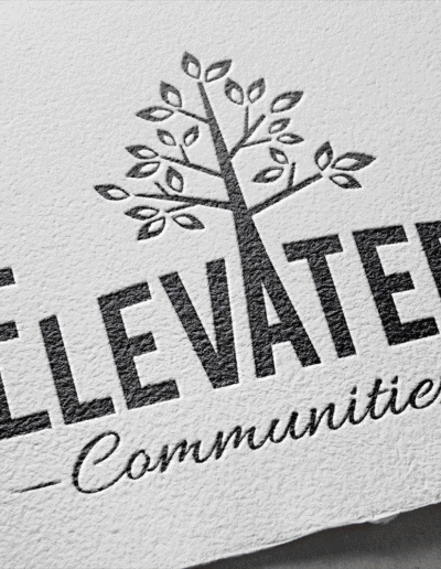 Embossed logo of Elevated Communities featuring a stylized tree with spreading branches and the text “Elevated Communities” printed below it.