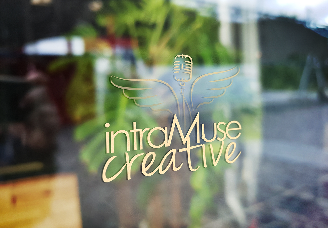 iMc-window-logo Gold foil logo for intraMuse Creative displayed on a glass window, featuring a vintage microphone with stylized wings above the brand name in a modern, artistic font.