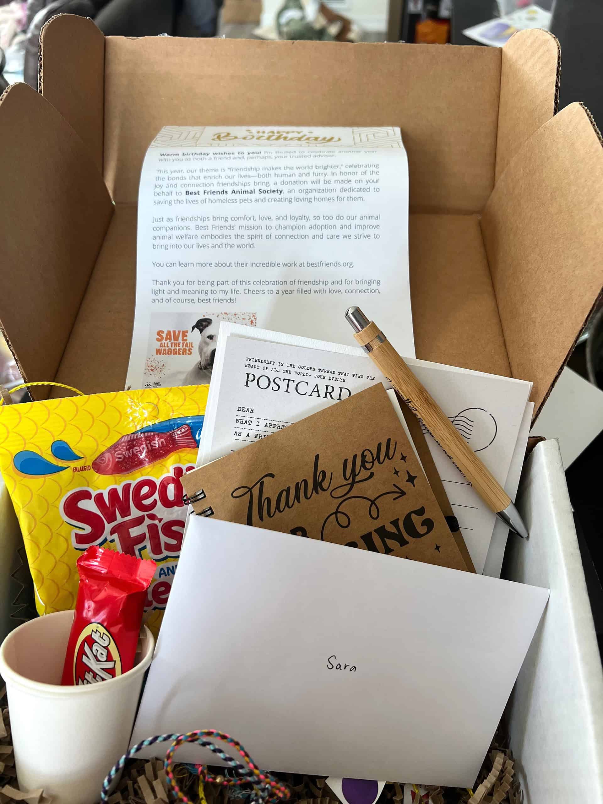 GWM- 2025 Birthday Box Gift box from Generosity Wealth Management featuring a letter about Best Friends Animal Society, Swedish Fish candy, a thank-you notebook, postcard, pen, and personalized card for the recipient.